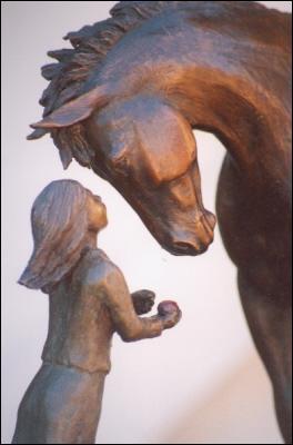 Horse sculpture of young girl feeding her horse an apple.  Sculpture titled First Love